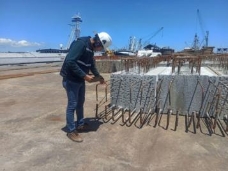 A person wearing a white helmet and standing next to a pile of concrete

Description automatically generated