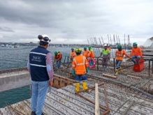 A group of men in orange vests and helmets standing on a dock

Description automatically generated