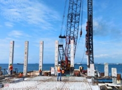 A construction site with cranes and a body of water

Description automatically generated